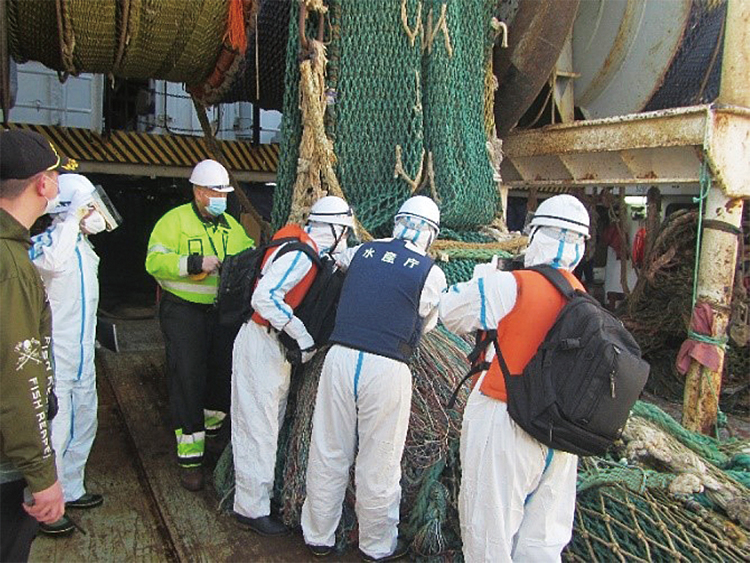 防護服を着て、外国漁船への立入検査を行う漁業監督官