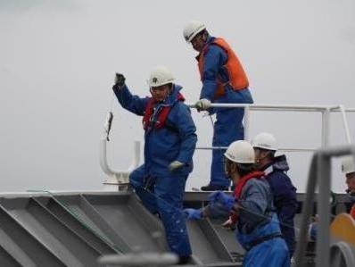 甲板上ではえ縄を引き上げる漁業取締船乗組員