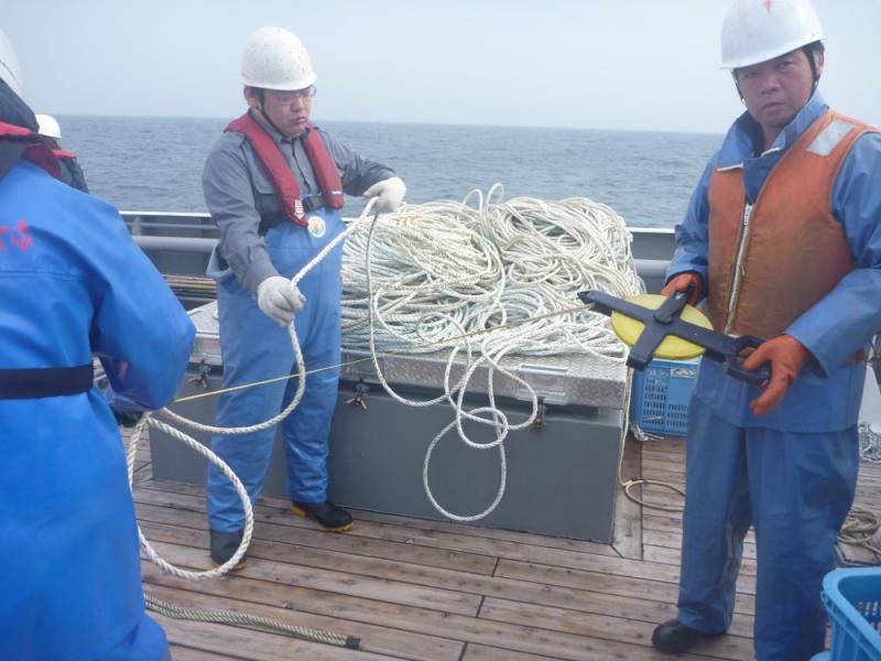 甲板上でロープの長さを測る漁業取締船乗組員
